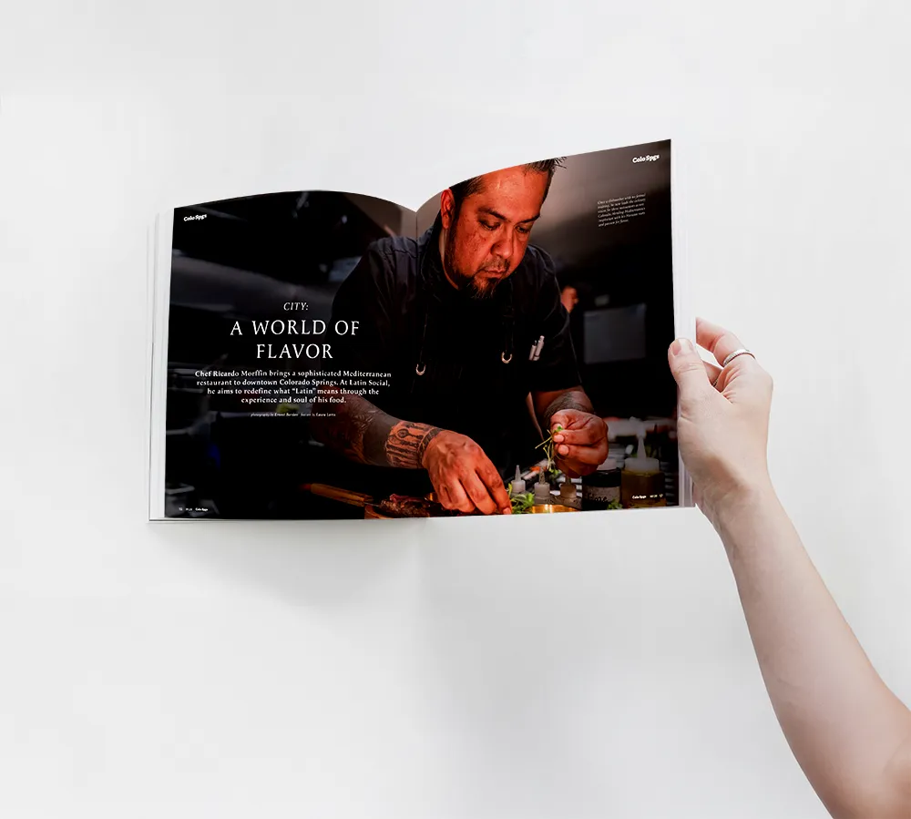 A reader holding Colorado Springs Magazine open to the “A World of Flavor” feature
